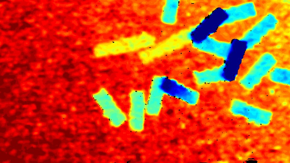 Colorized depth frame: blocks appear blue against a red table, with black dropout speckles